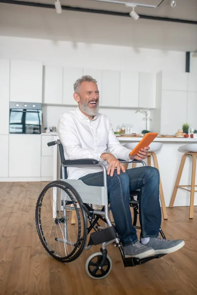 Gray-haired handicapped man with a tablet in hands — Stock Photo, Image