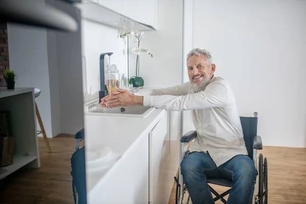 Homem deficiente de cabelos grisalhos na cozinha preparando o café da manhã — Fotografia de Stock