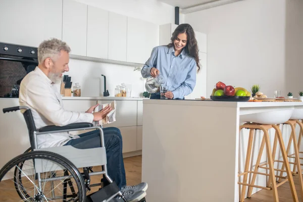 Homem deficiente de cabelos grisalhos e sua esposa em casa antes do café da manhã — Fotografia de Stock