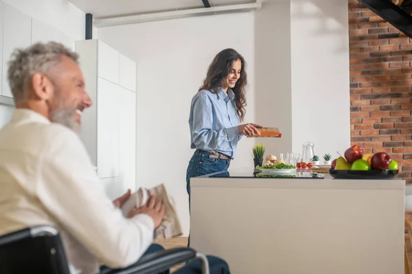 Homem deficiente de cabelos grisalhos e sua esposa em casa antes do café da manhã — Fotografia de Stock