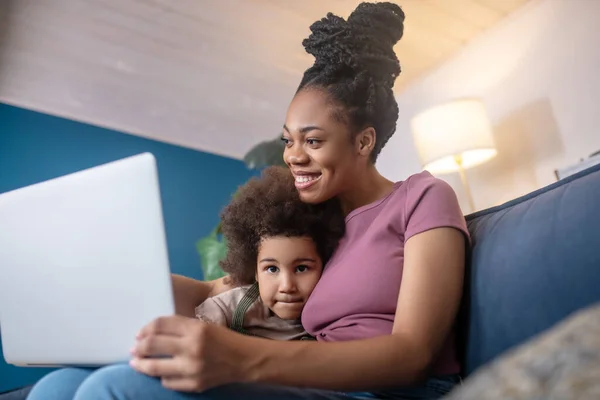 Abrazando mamá y niña mirando a la computadora portátil — Foto de Stock