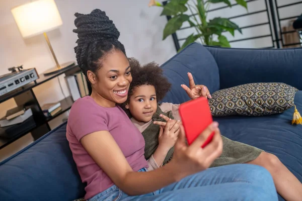 Mom and daughter with smartphone showing wellbeing gesture — Stock Photo, Image