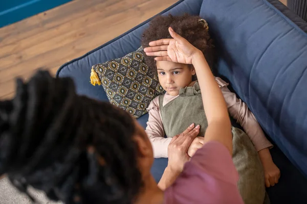 Mutter berührt Stirn eines kranken kleinen Mädchens mit Handfläche — Stockfoto