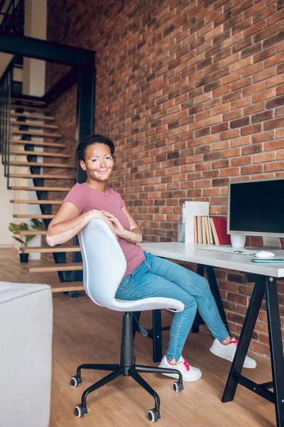 Молодая африканская американка, сидящая за столом на рабочем месте — стоковое фото