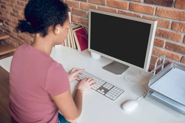 Ung afrikansk amerikansk kvinna sitter vid bordet på sin arbetsplats och ser upptagen ut — Stockfoto