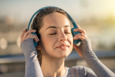 Waist up picture of a girl in headphones looking enjoyed clipart