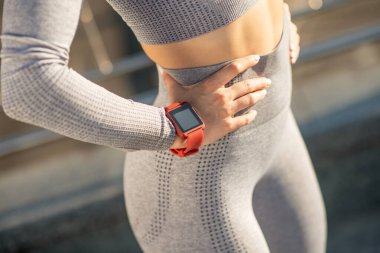 Close up picture of a female in grey sportswear and with a smartwatch on her wrist