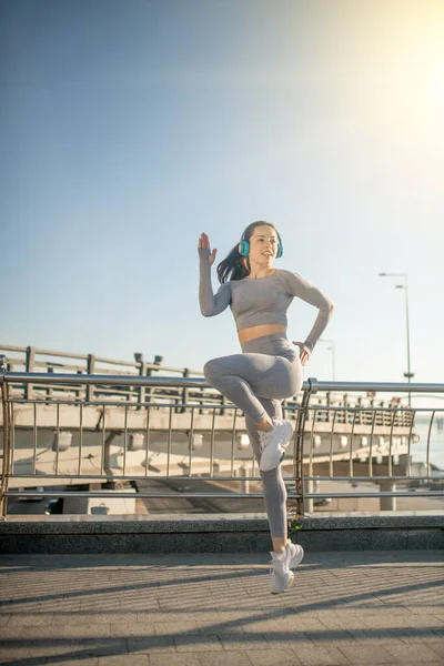 Fit girl in grey sportswear jumping during her warm up exercising — Foto de Stock