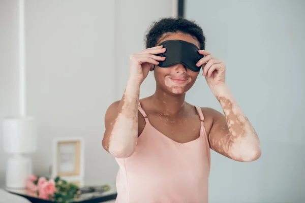 Young mulatta putting on a mask for sleep — Stock Fotó