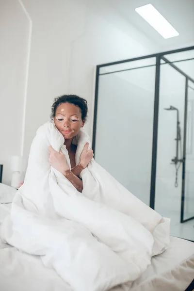 담요덮인 침대에 앉아 편안 함을 느끼는 젊은 여자 — 스톡 사진