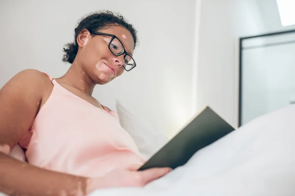 Young woman sitting in bed and watching something on a laptop — Foto de Stock