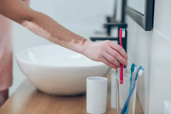 Picture of a woman putting the teeth brush to the glass — Foto de Stock