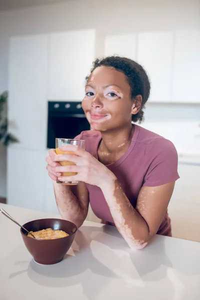 Молодая темнокожая женщина держит стакан с апельсиновым соком — стоковое фото