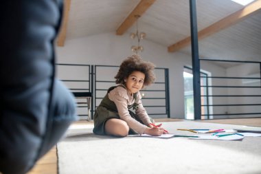 Smiling little girl drawing with color pencils