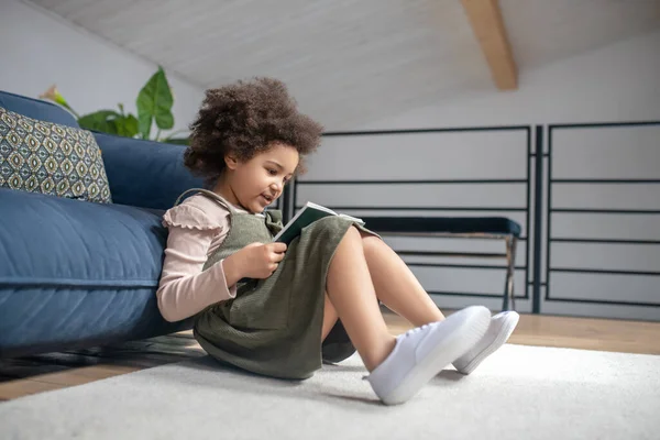 Щаслива дівчинка читає книгу на підлозі — стокове фото