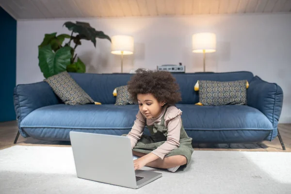 Маленькая африканская американская девочка сидит на полу с ноутбуком — стоковое фото