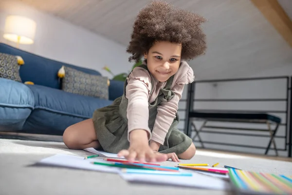 Kleines Mädchen wählt Buntstift auf dem Fußboden — Stockfoto