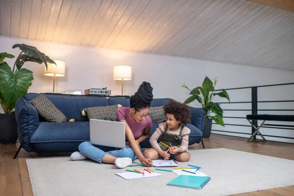 Mujer atenta ayudando a la niña a dibujar —  Fotos de Stock