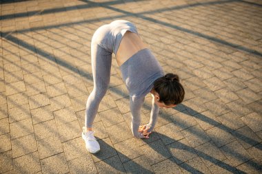 Genç bayan sporcu dışarıda spor yapıyor.