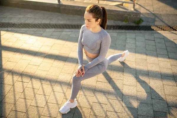 Młoda dziewczyna w szarym stroju sportowym ćwiczy na zewnątrz — Zdjęcie stockowe