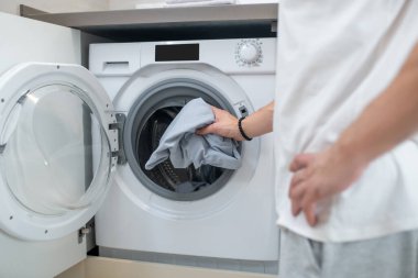 Erkek ellerinin çamaşır makinesini açtığı resmi kapat.