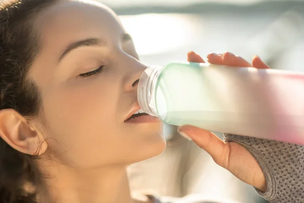 Молодая девушка пьет воду после тренировки — стоковое фото