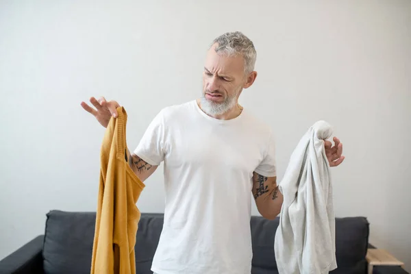 Un hombre de pelo gris que parece infeliz mientras piensa en lavar la ropa — Foto de Stock
