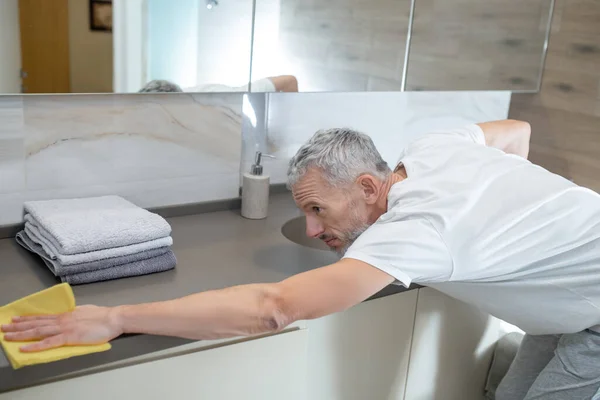 Un hombre con una camiseta blanca haciendo tareas domésticas y limpiando — Foto de Stock