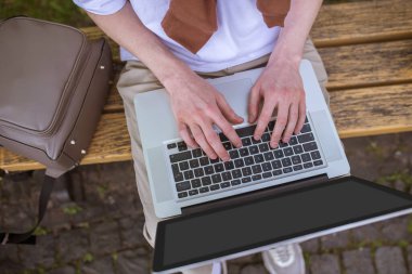 Bir dizüstü bilgisayarla bankta oturup,