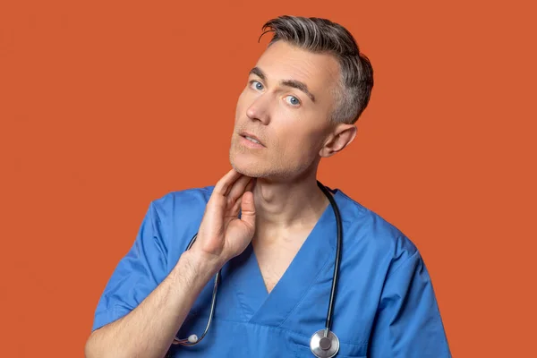 Man met stethoscoop die de hand aan zijn nek raakt — Stockfoto