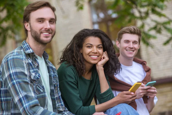 Fiatalok csoportja ül a behcn-en és okostelefonokat tart a kezében — Stock Fotó
