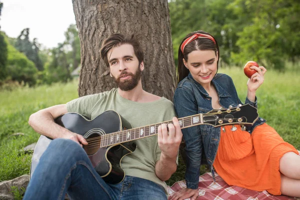 Guy spelen gitaar en meisje eten appel — Stockfoto