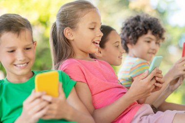 Akıllı telefon ve arkadaşlarına bakan hevesli bir kız.