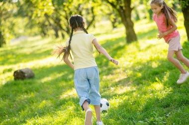Futbol topuyla koşan iki kız.