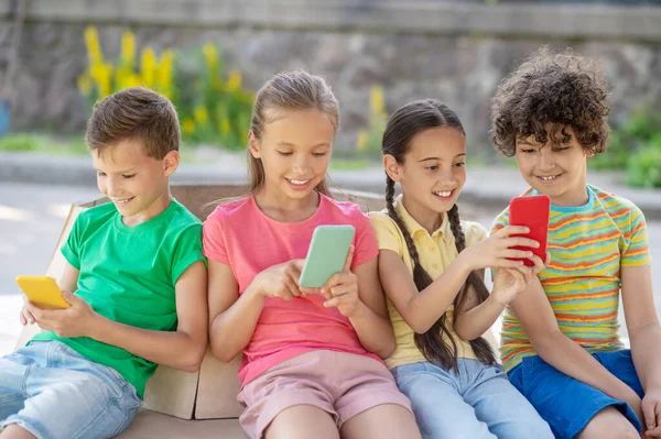 Niños y niñas con teléfonos inteligentes al aire libre —  Fotos de Stock