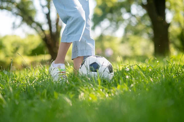 Pies de niño menor con pelota de fútbol en la hierba — Foto de Stock