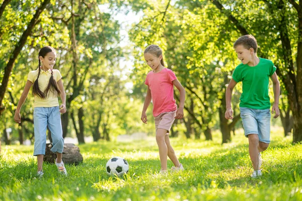 Oğlan ve iki kız arkadaş futbol oynuyor. — Stok fotoğraf