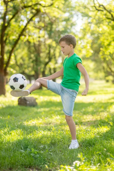 Garçon frapper ballon de football sur la pelouse — Photo