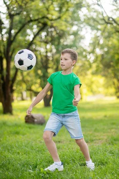 Jeune garçon jouant au ballon de football dans le parc — Photo