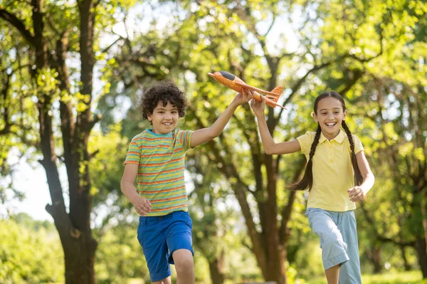 Chica y niño con juguete avión corriendo en el parque — Foto de Stock