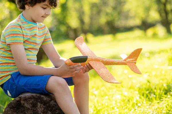 Niño mirando avión de juguete en la naturaleza — Foto de Stock