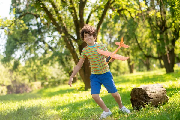 Garçon énergique jouant avec un avion jouet sur la pelouse — Photo