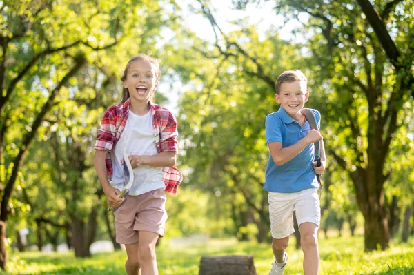 Ridere ragazzo e ragazza in esecuzione nel parco — Foto Stock