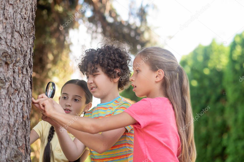 Boy with magnifying glass and two girls