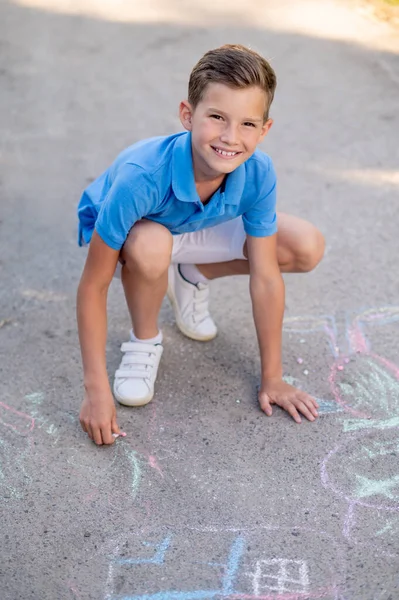 Boy with crayon crouched down to paint