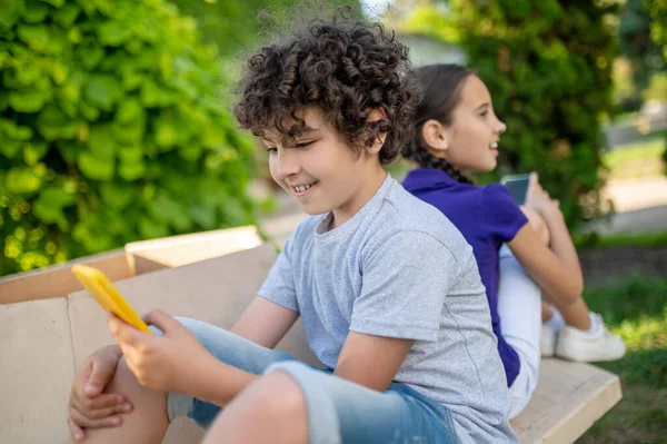 Enfants avec smartphones dans un parc vert — Photo