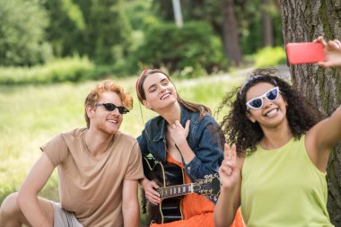Arkadaşlar piknikte akıllı telefondan selfie çekiyorlar.