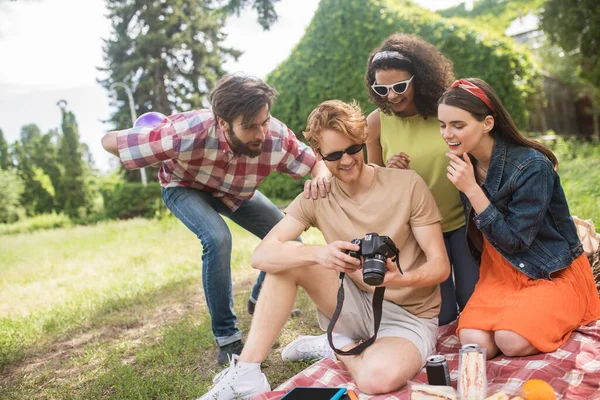 Amigos viendo fotos descansando en el picnic —  Fotos de Stock