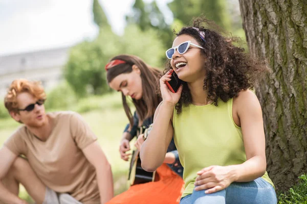 Menina alegre falando no smartphone e amigos — Fotografia de Stock