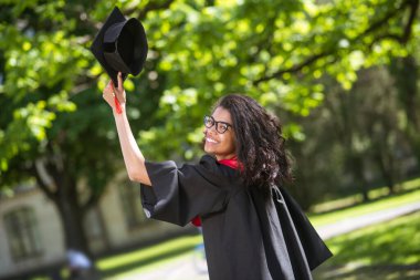 Koyu renk saçlı mezun mezuniyet için mutlu ve heyecanlı hissediyor.